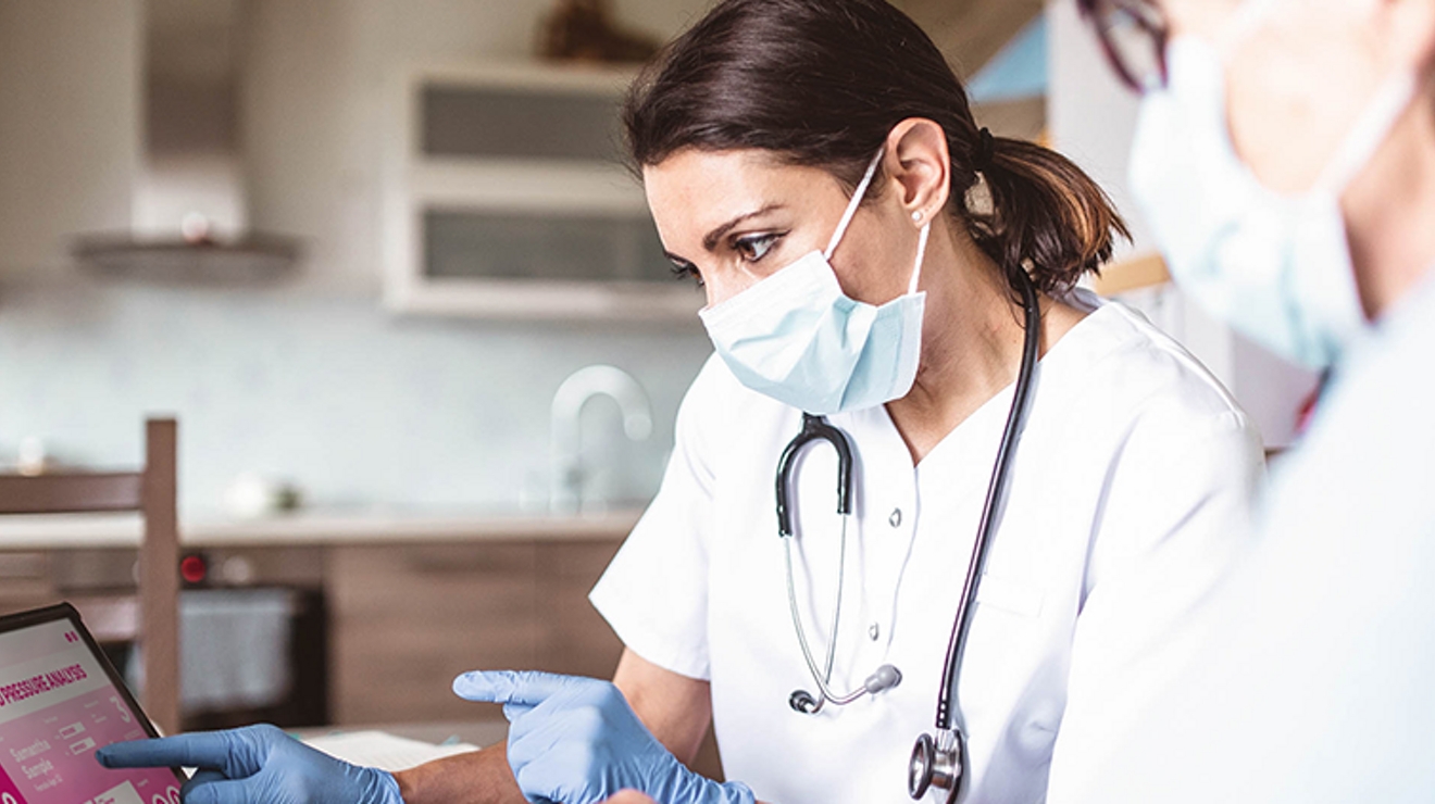 Medical professional shows patient a tablet with blood pressure readings on screen